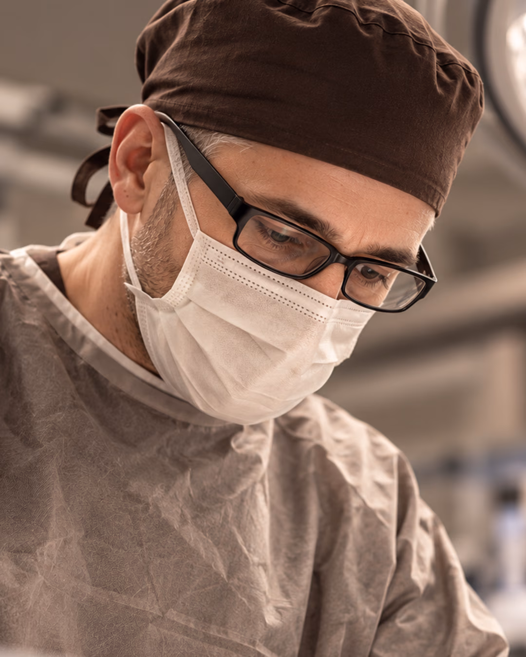 Surgeon in theatre cap and mask, concentrating during surgery